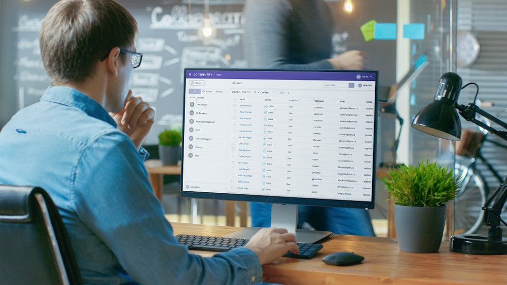 Man vid skrivbord övervakar användardata i ett MDM-system på datorskärm.